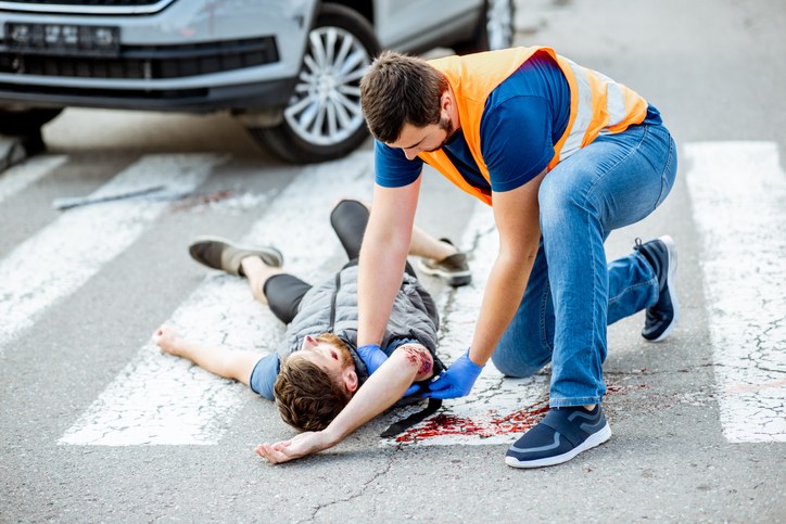 Man Aiding an Injured Pedestrian After a Road Accident