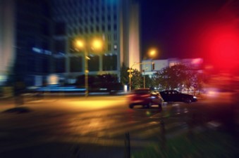 Two cars are moving on the road at night in Las Vegas, NV